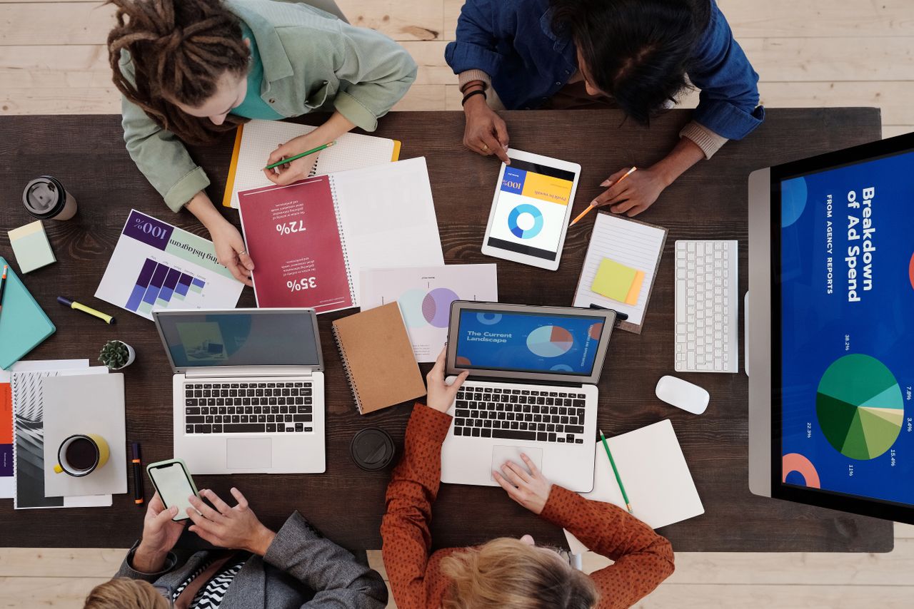 Une équipe variée travaillant ensemble sur des stratégies de marketing numérique autour d’un bureau, avec des ordinateurs portables et des tablettes.